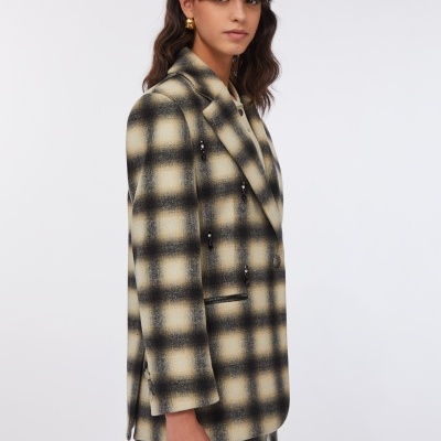 Blazer feminino xadrez bege e preto com detalhes de botões, usado com saia curta correspondente e fundo branco