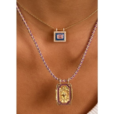 Dois colares dourados com pendentes retangulares, um com pedra rosa e detalhes azuis, outro com corrente trançada roxa e dourada e design dourado em relevo.