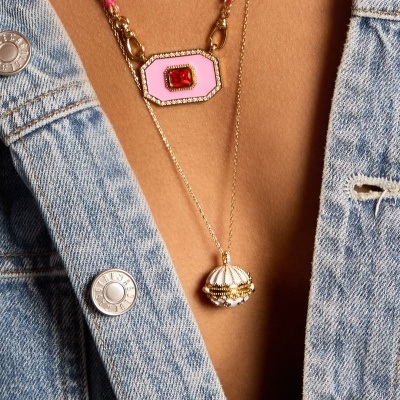 Colares dourados com pingentes rosa e branco usados com casaco de ganga azul claro.