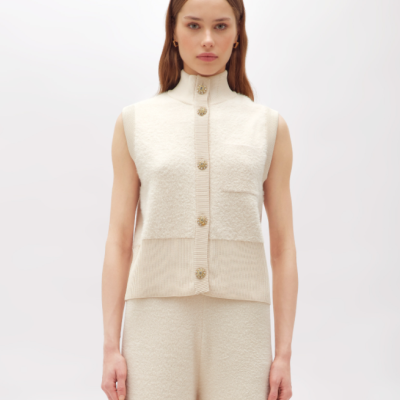 Blusa feminina creme sem mangas com botões dourados na frente e gola alta, e calças largas creme no mesmo tecido.