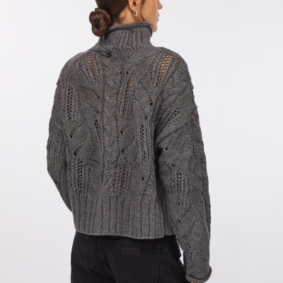 Mulher com camisola cinzenta de malha grosso com padrão trançado e gola alta