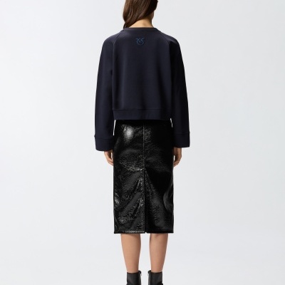 Mulher de costas com sweatshirt azul e saia lápis preta brilhante.