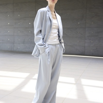 Mulher vestindo fato azul claro riscado, t-shirt branca, sapatos brancos e óculos de sol quadrados