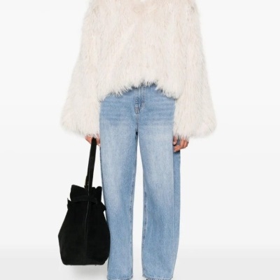 Mulher com camisola felpuda branca, calças ganga azuis, sapatos pretos e mala preta