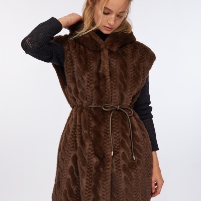 Colete castanho em pelúcia com cinto fino castanho sob vestido preto.