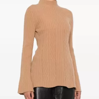 Camisola de malha bege com gola alta e mangas largas, usada com calças de couro pretas.