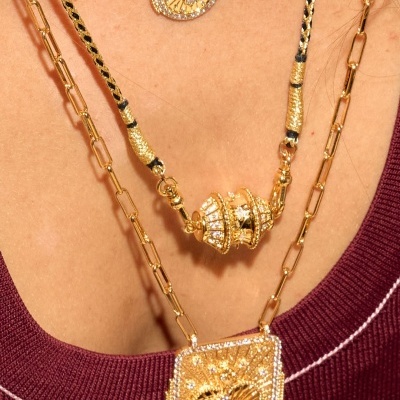 Colares dourados com pendentes brilhantes sobre camisola vinho.