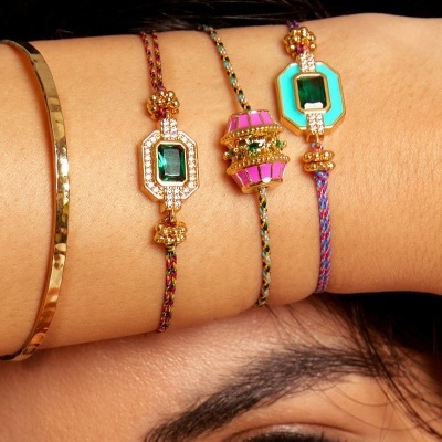 Pulseiras coloridas e douradas com pedras em cordão trançado no pulso