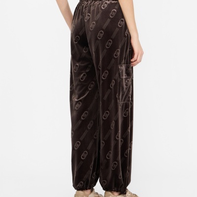 Calças castanhas de tecido aveludado com padrão repetido de logótipo e bolso lateral