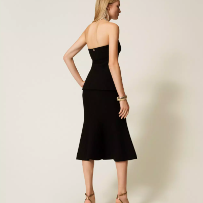 Mulher vista de costas a usar vestido preto midi com alças finas e salto alto castanho.