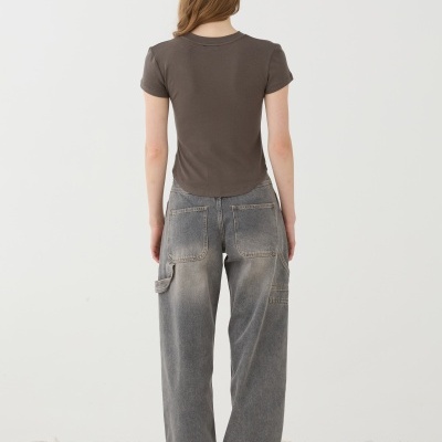 Mulher vista de costas com t-shirt castanha escura e calças largas cinzentas de ganga com bolsos grandes.