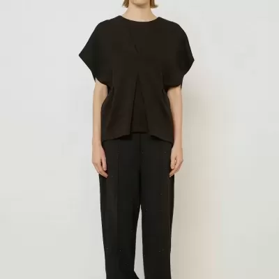 Conjunto t-shirt preta e calças largas pretas com sapatilhas prateadas.