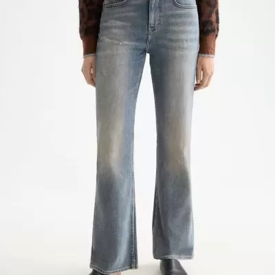 Calças de ganga azuis lavagem desbotada com cintura alta e bolsos, usadas com camisola castanha padrão animal e sapatos pretos.