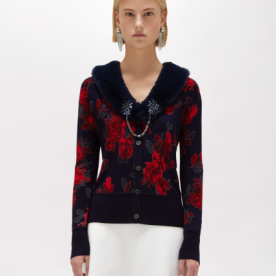 Cárdigan floral vermelho e preto com gola de pêlo azul escuro e saia branca.