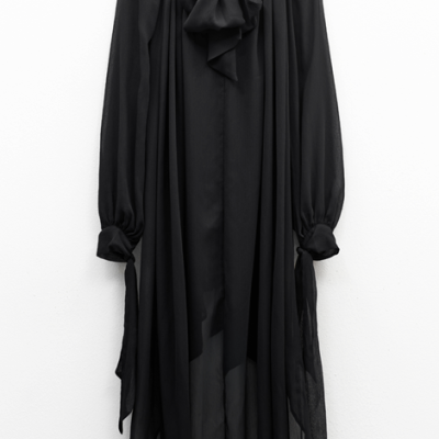 Vestido preto fluído com laço no pescoço pendurado na parede
