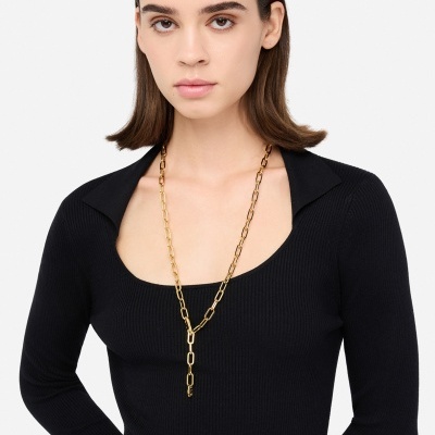 Colar dourado com elos grandes em modelo com camisola preta de malha.