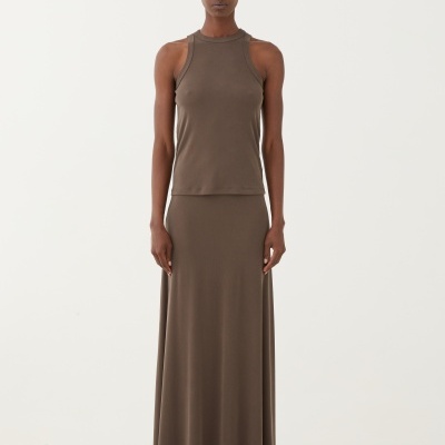 Conjunto castanho com top e saia comprida, sandálias plataforma preta, modelo em fundo branco com pedras brancas