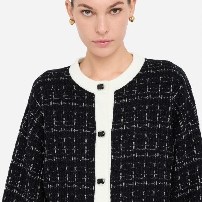 Cardigã preto com riscas brancas e botões pretos com moldura prateada.