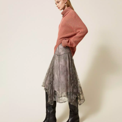 Mulher vestindo camisola rosa, saia cinza translúcida com padrão floral e botas pretas