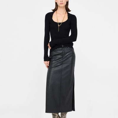 Mulher com camisola preta de malha, saia preta em pele e botas com padrão de pele de cobra.