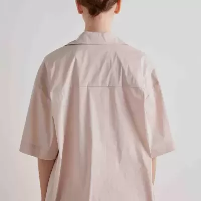 Camisa bege clara de manga curta vista de costas com cabelo preso