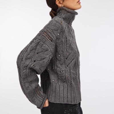 Mulher com pulôver cinzento de malha com lantejoulas e gola alta