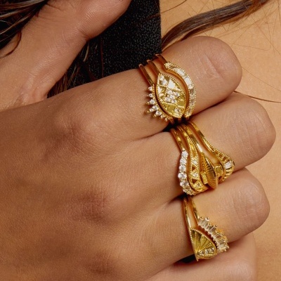 Mão com três anéis dourados com pedras brancas brilhantes