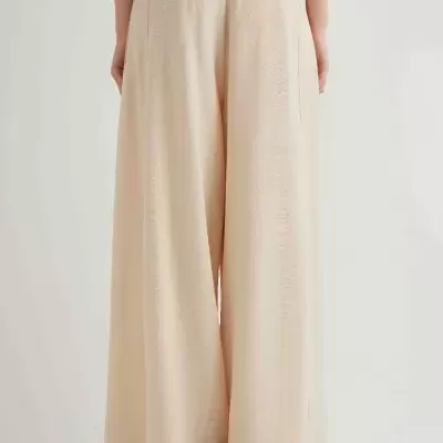 Calças compridas bege claro com corte largo, vistas de costas