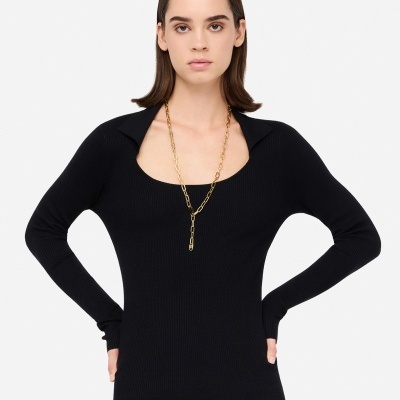 Camisola preta de malha com decote quadrado e gola, colar dourado e saia preta de pele.