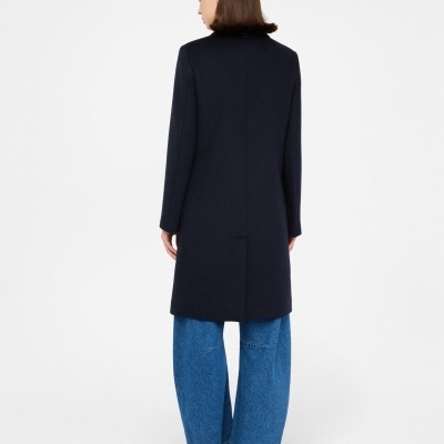 Casaco comprido preto visto de trás com calças largas de ganga azuis