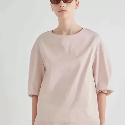 Pessoa com camiseta rosa claro e calças brancas com fitas largas