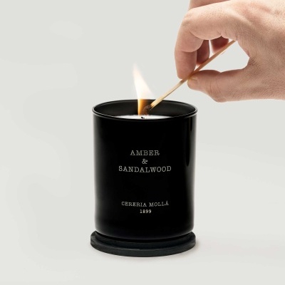 Vela perfumada preta com texto em branco a ser acesa