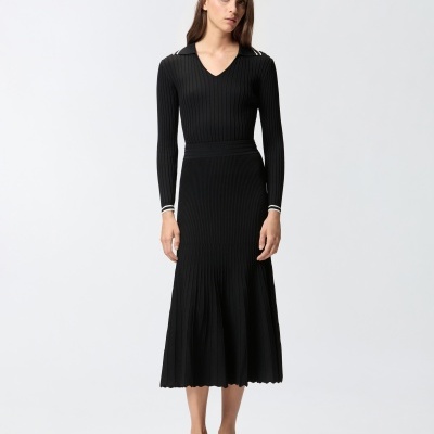 Vestido comprido preto de malha canelada com gola e punhos com risca branca, usado por mulher