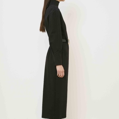 Mulher de perfil com vestido preto comprido e sapatos beije