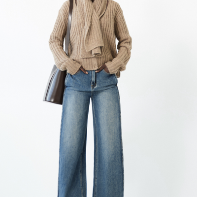 Mulher com cardigan castanho de malha, jeans largos azuis e mochila castanha