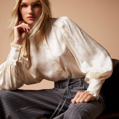 Blusa branca acetinada com padrão floral e calças cinzentas de riscas brancas