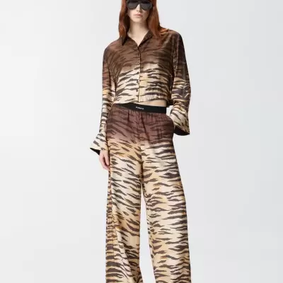 Conjunto de roupa com padrão animal castanho e bege, óculos de sol pretos, fundo branco.