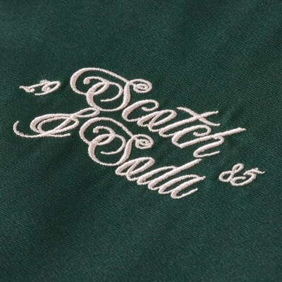 Detalhe bordado branco em tecido verde