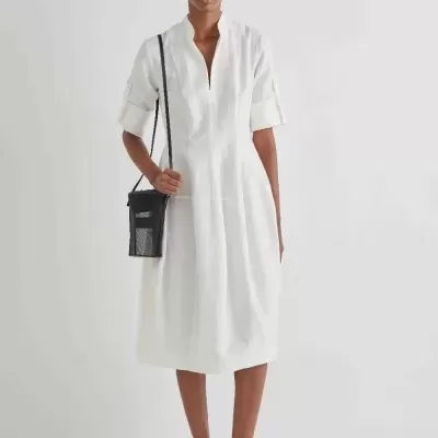 Vestido branco midi com gola aberta, sapatos pretos de salto médio e bolsa preta pequena