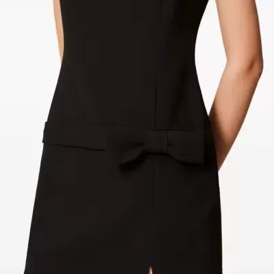 Vestido preto curto com laço e corte na bainha.