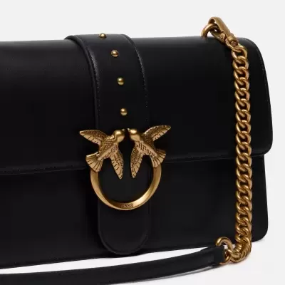 Mala preta de couro com fecho dourado com pássaros e corrente dourada.