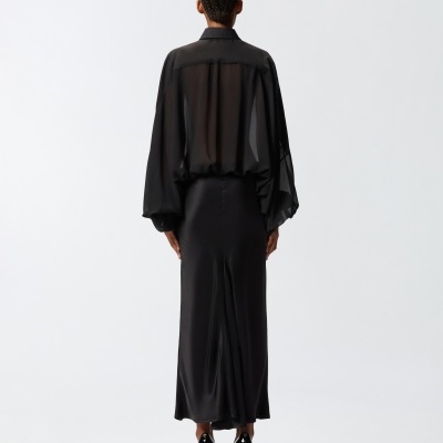 Mulher de costas com camisa preta transparente e saia preta longa