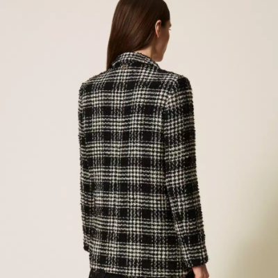 Casaco xadrez preto e branco visto de costas, sobre fundo neutro