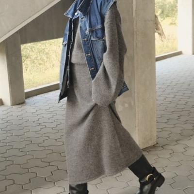 Vestido cinza de malha com colete de ganga azul e botas pretas em chão de tijoleira hexagonal