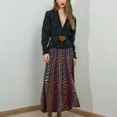 Mulher com casaco preto texturizado e saia longa de padrões verticais coloridos