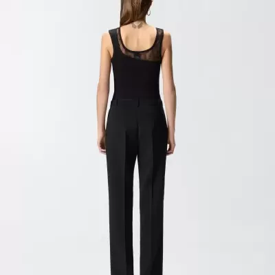 Mulher de costas com camisola preta com renda e calças pretas.