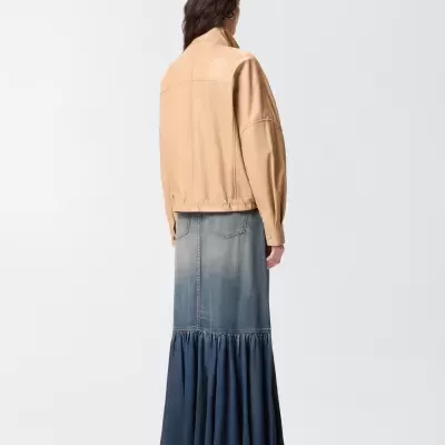 Pessoa de costas com casaco bege e saia longa azul de ganga