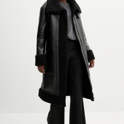 Mulher a usar casaco preto comprido de couro com pêlo sintético e calças pretas