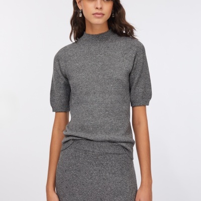 Mulher com camisola cinza de manga curta e saia cinza comprida em malha brilhante