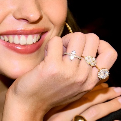 Mulher sorridente a mostrar anéis de ouro com pedras brilhantes